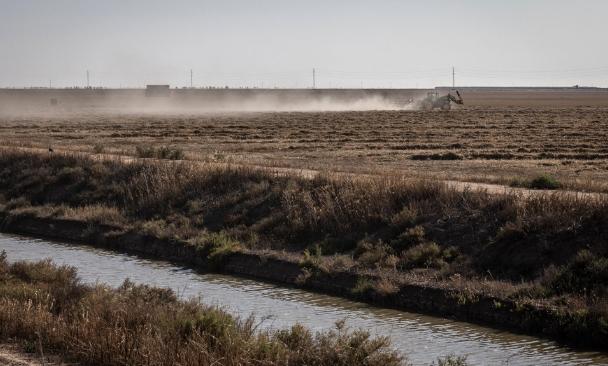Un tractor atraviesa un campo agrícola regado por un canal de agua cerca del parque nacional de Doñana